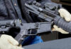 Person assembling a black rifle with gloves on.