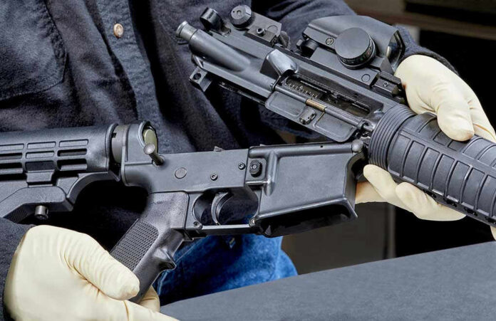 Person assembling a black rifle with gloves on.