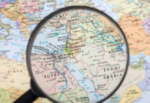 Magnifying glass over Middle East map highlighting Israel and Egypt.
