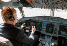 Pilot in cockpit operating airplane controls.