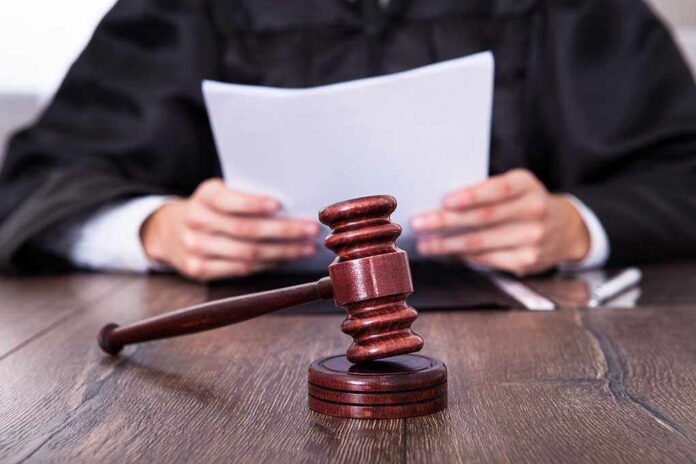 A judge holding documents with a gavel in the foreground