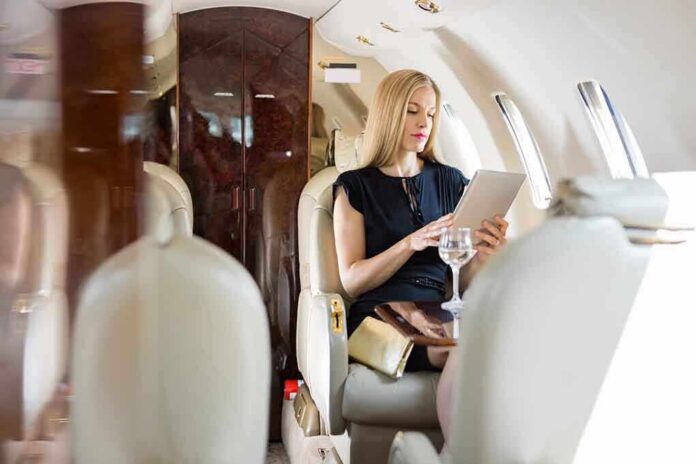 A woman in a private jet using a tablet while seated elegantly