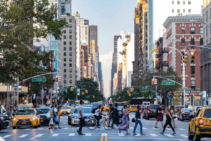 Busy city street with cars and people crossing.