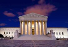 The Supreme Court building illuminated at night with a clear sky
