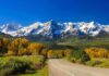 Unbelievable! Route 66’s Centennial Revival Scenic view of snow-capped mountains with autumn trees and a winding road