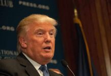 A public figure speaking at a podium during a press conference