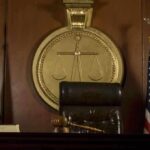 A judges bench in a courtroom with a gavel and flags