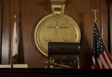 A judges bench in a courtroom with a gavel and flags