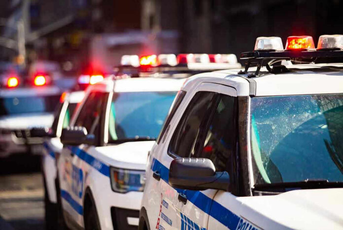 1375359047 Police cars with flashing lights in line formation.