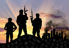 SHOCK: Nigeria-U.S. Kill World’s ‘Most Active’ Terrorist Three armed silhouettes near a smoky city skyline.