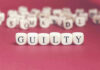 Dice spelling GUILTY on a red surface.