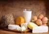 Assorted dairy products including cheese, milk, and eggs on a wooden surface