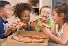 Junk Food Rewires Kids’ Brains—Alarming New Study Four children joyfully sharing slices of pizza around a box