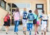 AI Takeover: Teachers in Control? Group of children walking towards a school entrance with backpacks