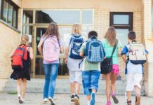 AI Takeover: Teachers in Control? Group of children walking towards a school entrance with backpacks