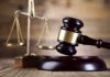 A wooden gavel and scales of justice on a wooden surface