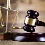 Surprise Twist in Elite Murder Trial A wooden gavel and scales of justice on a wooden surface