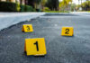 Italian Car Mayhem: Accident or Attack? Crime scene markers on asphalt with bullet casing.