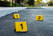 Italian Car Mayhem: Accident or Attack? Crime scene markers on asphalt with bullet casing.
