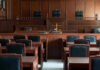 Tax-Funded Threats Target Congresswoman Empty courtroom with wooden furnishings and judges bench.