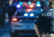 Bloody Weekend Ignites Trump vs. Pritzker Police officer with patrol car and flashing lights.