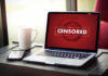 Printer Police Hit New York Laptop screen displaying CENSORED beside coffee and phone