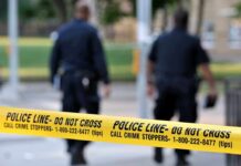 Police officers walking past caution tape at a crime scene
