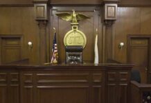 Interior of a courtroom featuring a judges bench and American flag
