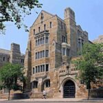 Historic university building with stone facade and surrounding trees
