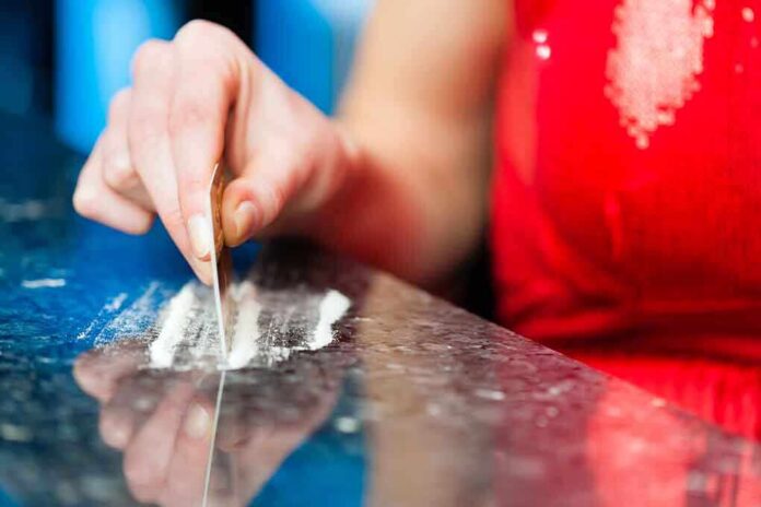 shutterstock_149840591 A hand using a card to prepare a line of white powder on a reflective surface