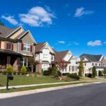 Housing Sticker Shock—Fed Points To Biden Era-Border A row of modern suburban houses under a clear blue sky