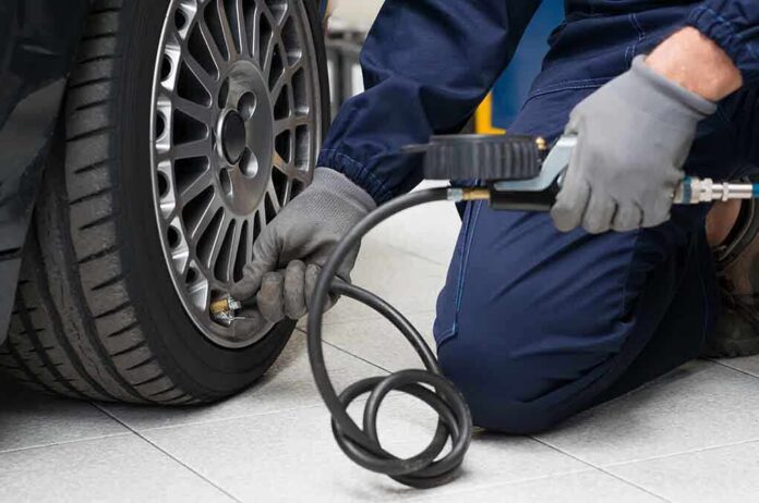 Mechanic inflating a car tire in a workshop