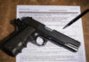 Supreme Silence Ignites Gun-Rights Chaos Gun and pen on firearm transaction form.