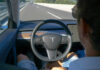 Deadly Dashboards? Regulators Look Away Person using autopilot in Tesla on highway.