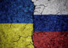 Power Brokers Carve Ukraine’s Future Cracked Ukrainian and Russian flags painted on concrete.