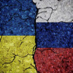 Power Brokers Carve Ukraine’s Future Cracked Ukrainian and Russian flags painted on concrete.