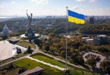 Winter Panic: Energy Boss Takes Power Large Ukraine flag with cityscape in background.