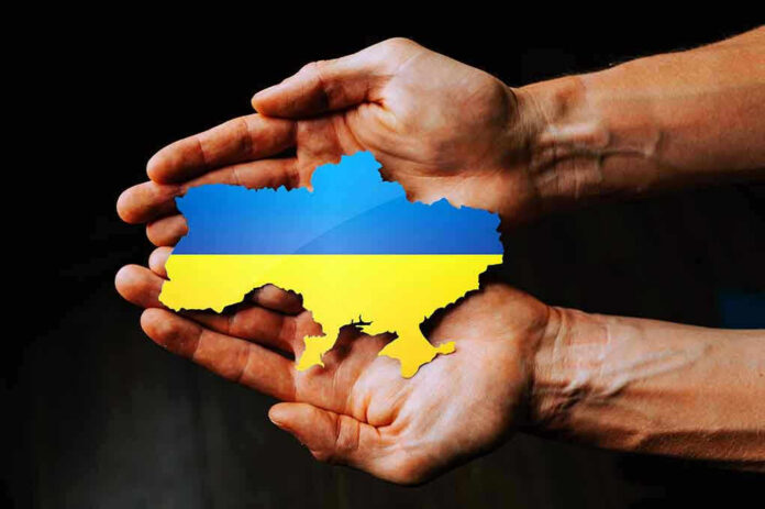 Hands holding Ukraine map with flag design.