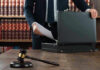 Backroom Brawl Over Who Picks Graham’s Seat Gavel, lawyer, briefcase, and legal books on the table.