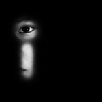 face peering through a keyhole in darkness