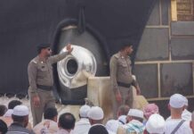 Two security personnel near the Kaaba during a religious gathering