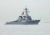 Trump Signals Tehran Will Pay Navy destroyer with crew lined on deck at sea