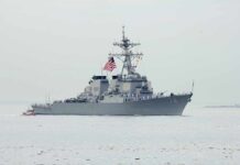 Navy destroyer with crew lined on deck at sea