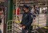 Elite Name-Drop Triggers Police Standoff Police officer stands in a subway station near caution tape