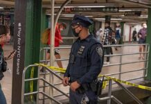 Elite Name-Drop Triggers Police Standoff Police officer stands in a subway station near caution tape