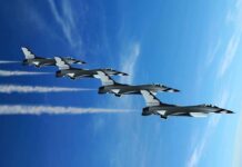 Thunderbirds ROAR Over D.C. Four military jets flying in formation against a blue sky, leaving smoke trails