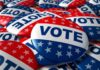 Trump Axes Election Umpires Weeks Out A pile of colorful buttons with the word VOTE and stars, symbolizing election participation
