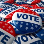 Trump Axes Election Umpires Weeks Out A pile of colorful buttons with the word VOTE and stars, symbolizing election participation