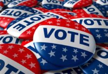 Trump Axes Election Umpires Weeks Out A pile of colorful buttons with the word VOTE and stars, symbolizing election participation