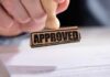 FDA vs. Kids? ZYN Flavors Survive A hand holding a wooden stamp with the word 'APPROVED' above a document